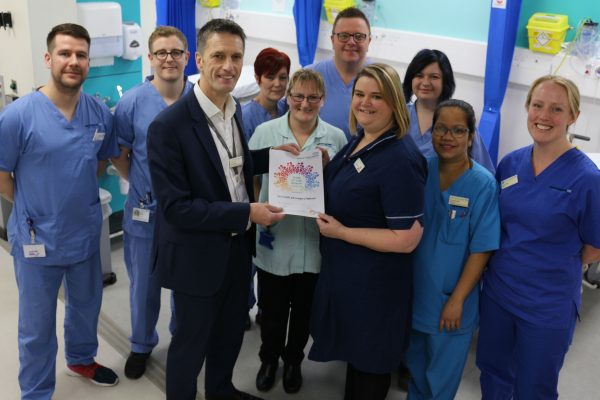 John Holden, director of strategy and integration, presents the Team of the Month award to A&E