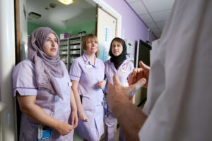 Three nurses chatting with a colleague.