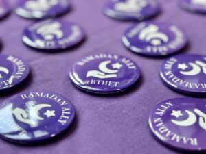 Purple Ramadan Allies badges on a purple tablecloth.