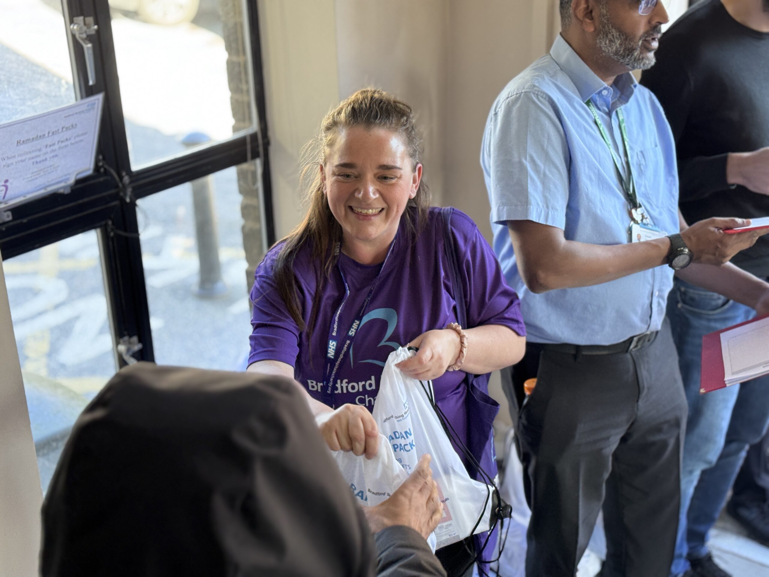 Charity team member handing out a FAST pack bag in the Muslim prayer facility.